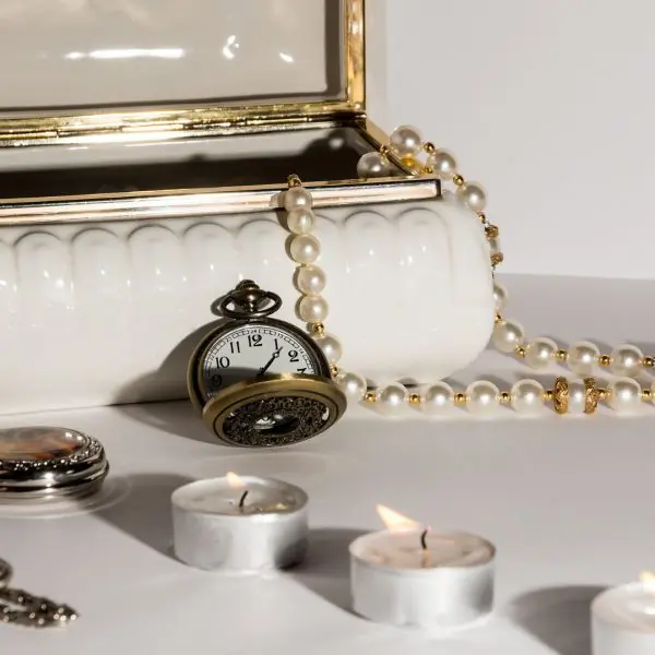 boite à bijoux avec des montres, un collier de perle et une pièce ancienne