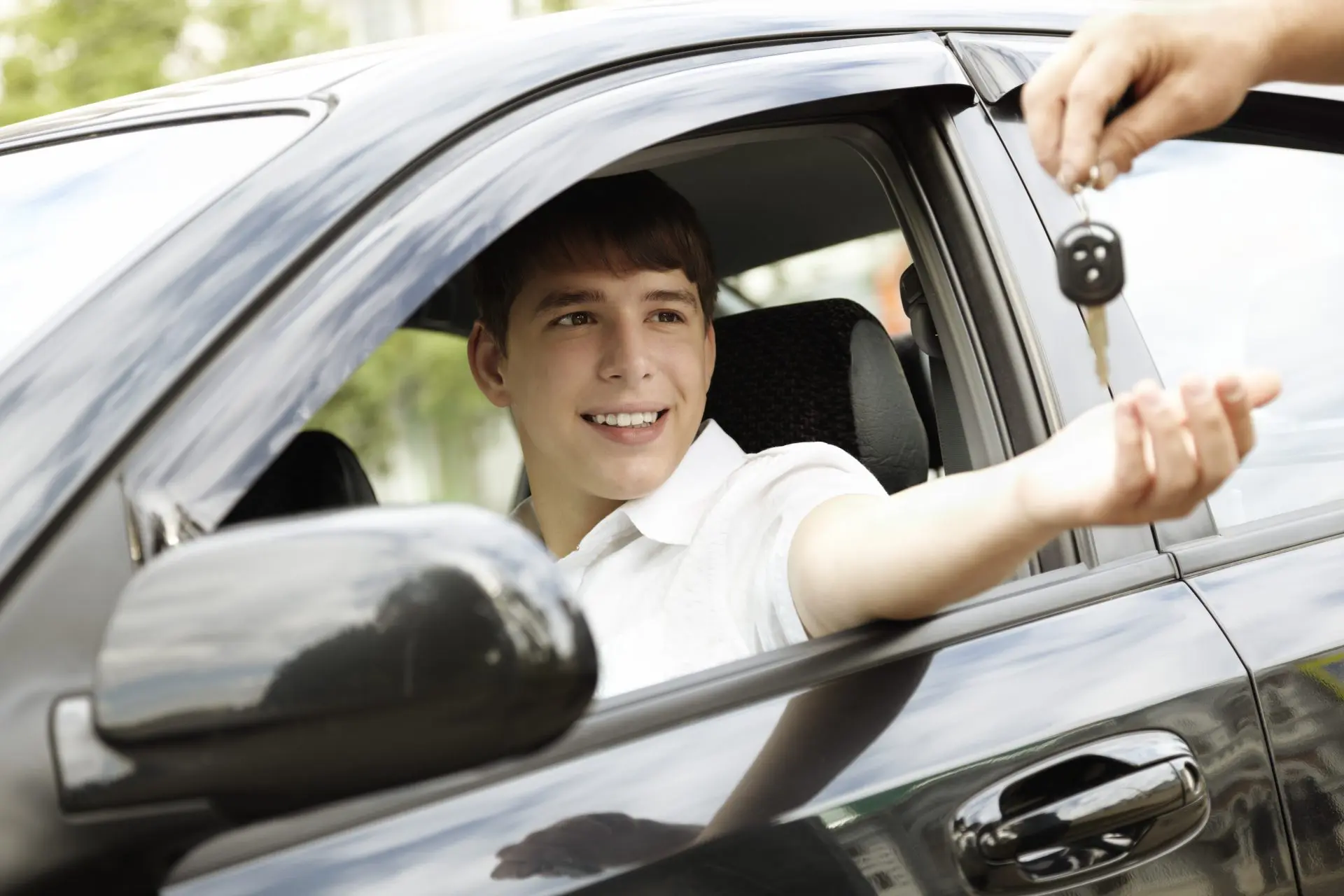 Jeune conducteur qui tend la main pour prendre des clés de voiture sans permis