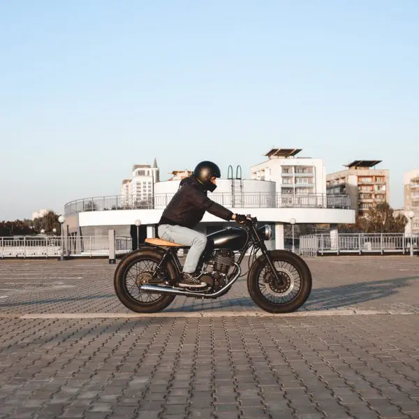 homme à dos de sa moto avec des buildings en fond