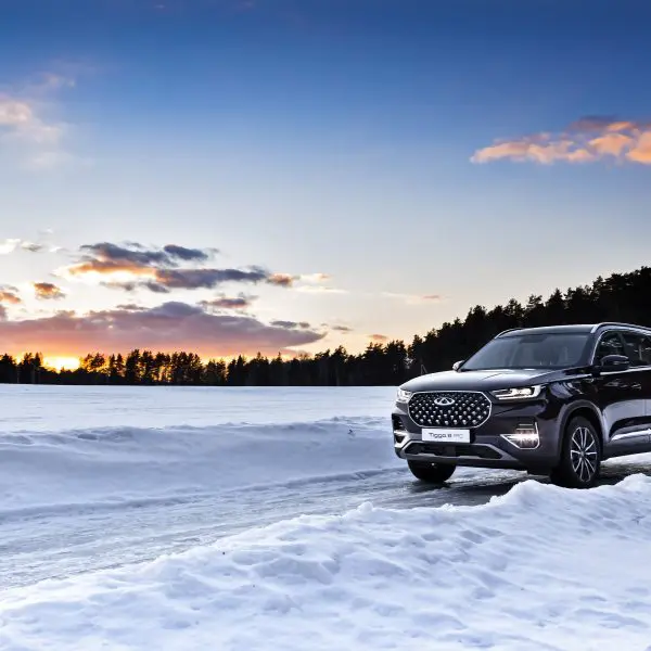 voiture qui roule au milieu de la neige avec le ciel, les nuages et le soleil qui se couche