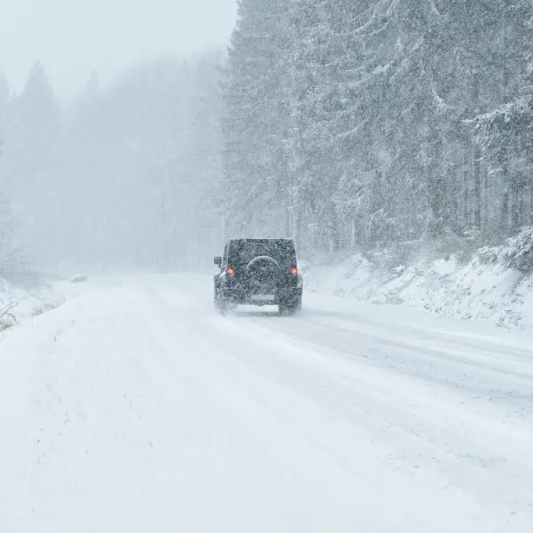 Pick-up qui roule sur une route enneigée avec des arbres autour