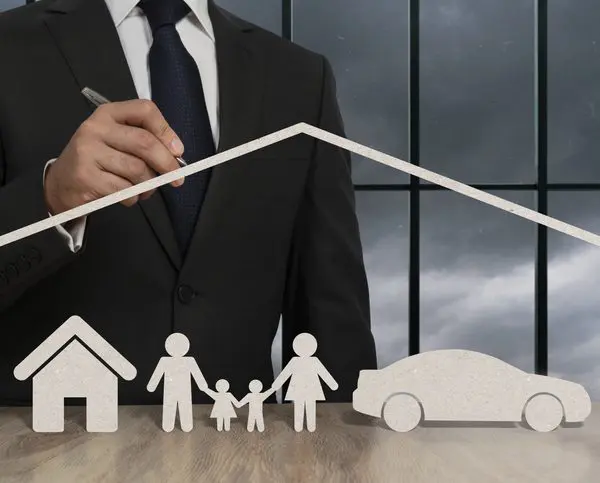 Homme qui pointe avec un stylo, un maison, une voiture et une famille en papier