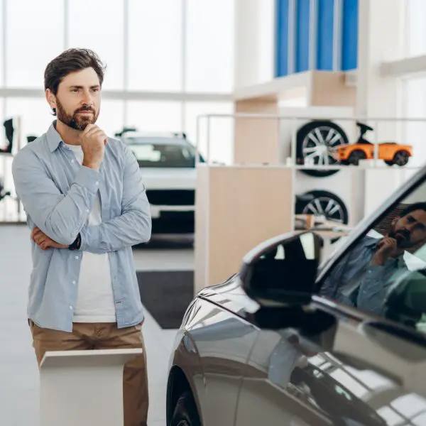 Le client qui choisit d’acheter une nouvelle voiture dans la salle d’exposition de la concession