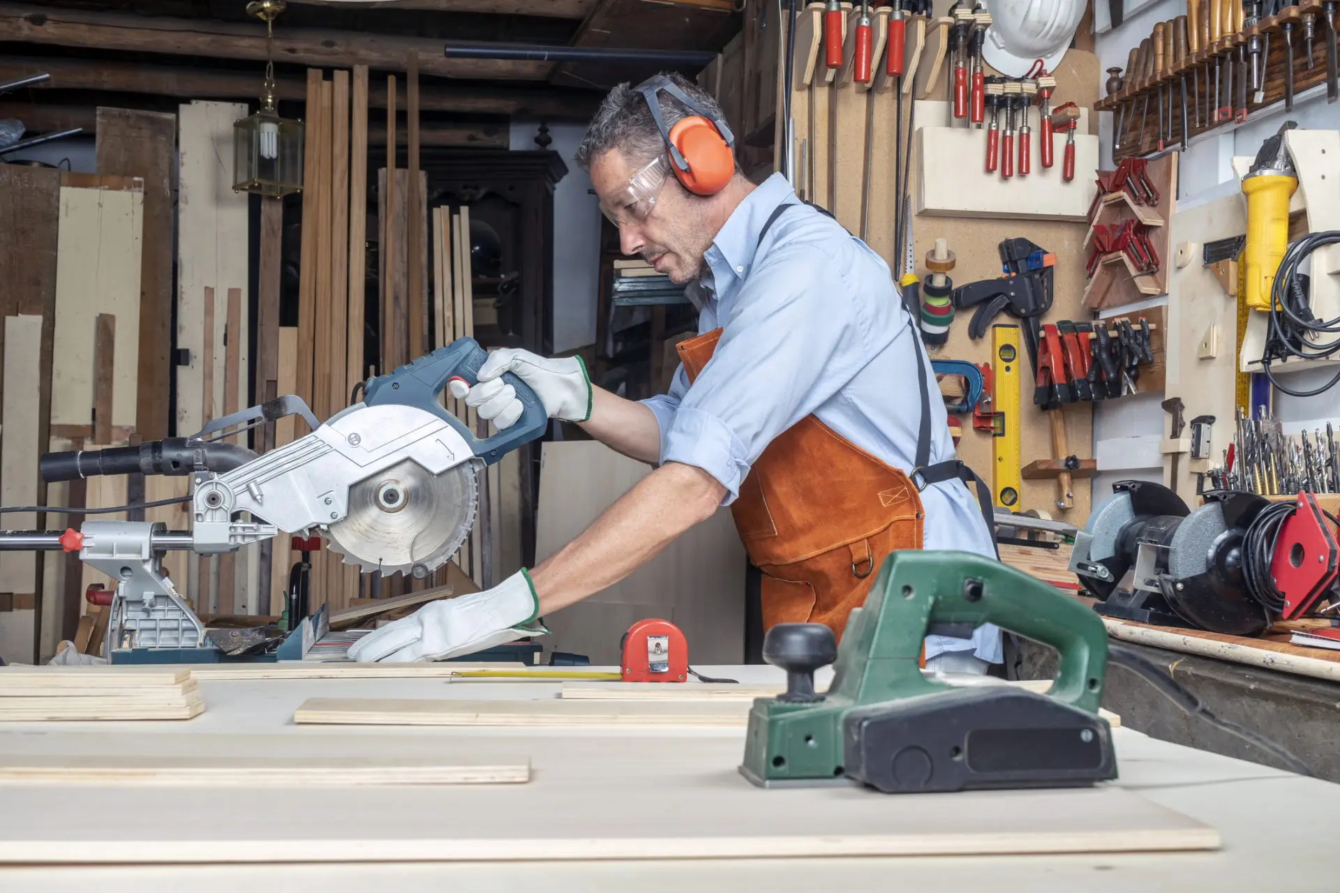 CHARPENTIER DANS L’ATELIER TRAVAILLANT LE BOIS À L’AIDE D’UNE SCIE À ONGLETS. CONCEPT DE BRICOLAGE.