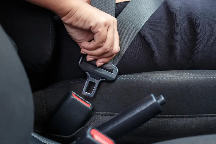 Gros plan d’une femme qui boucle la ceinture de sécurité de la voiture.