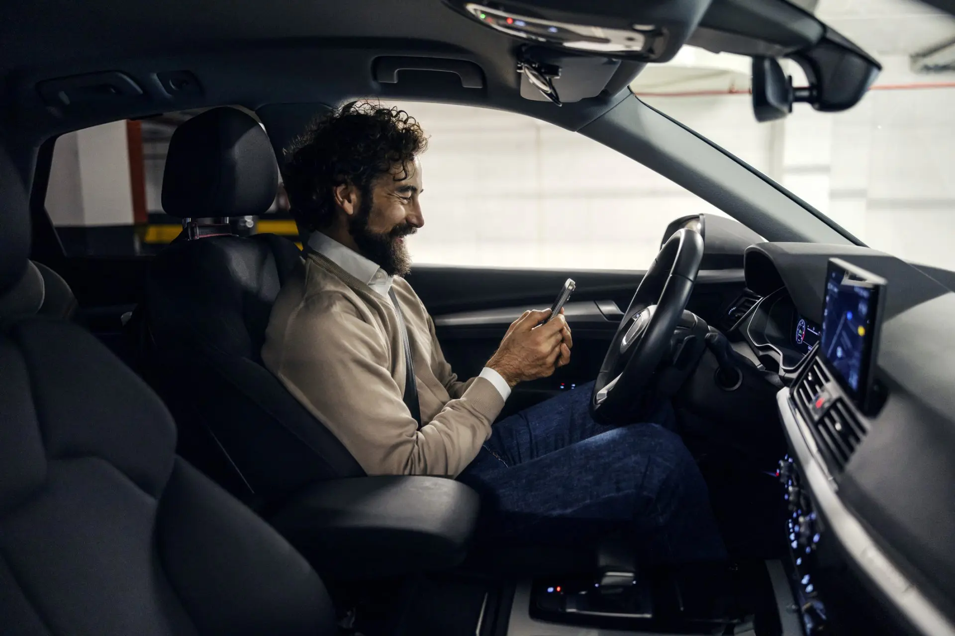 Homme souriant et envoyant des SMS à l’aide d’un smartphone dans la voiture