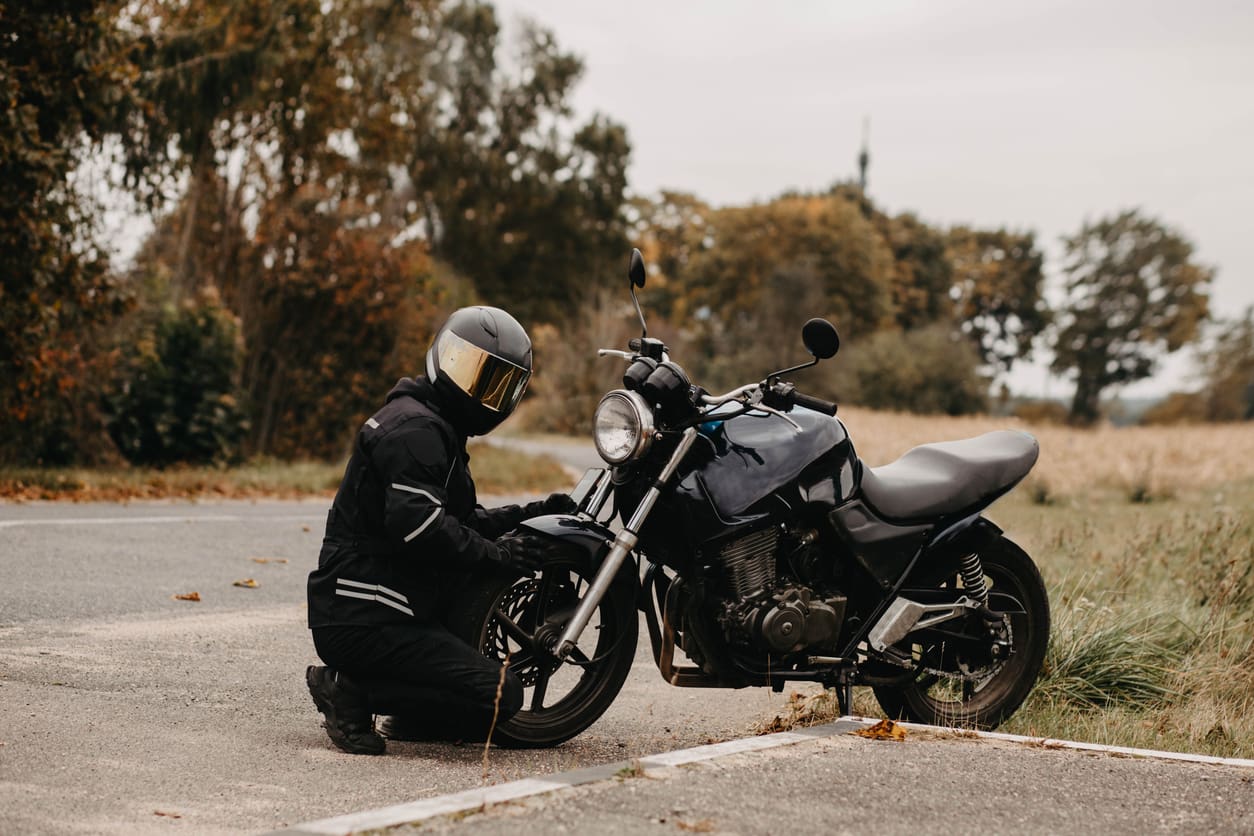 Motocycliste avec moto rétro sur la route en uniforme et casque.