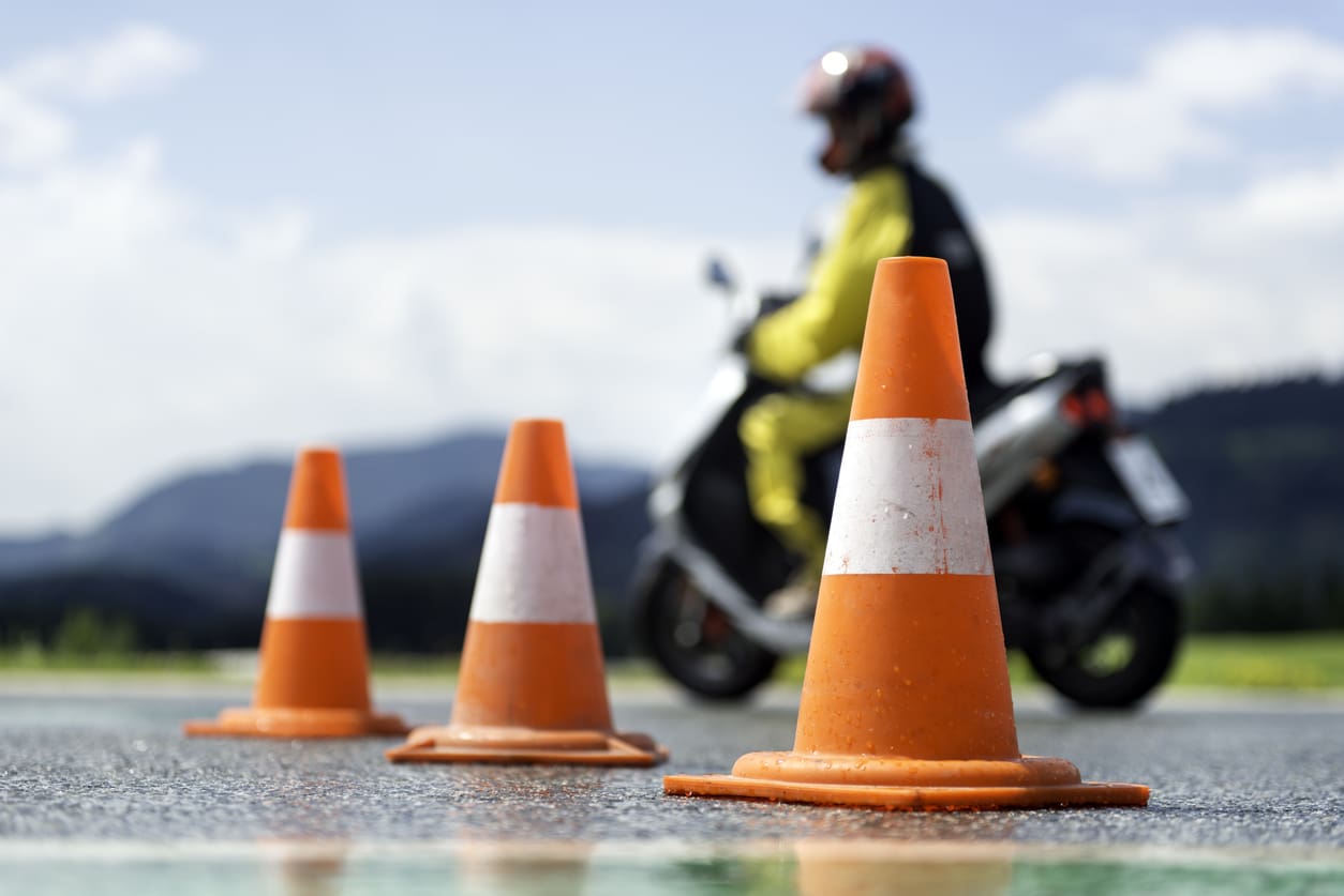 cônes de signalisation orange avec un scooter qui tente de manoeuvrer