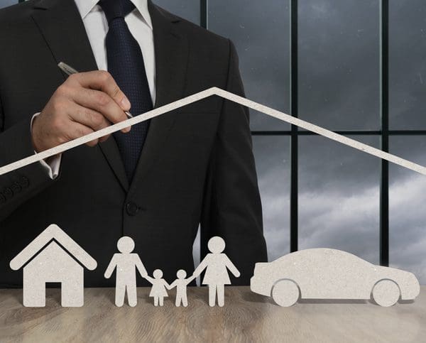 Homme qui pointe avec un stylo, un maison, une voiture et une famille en papier
