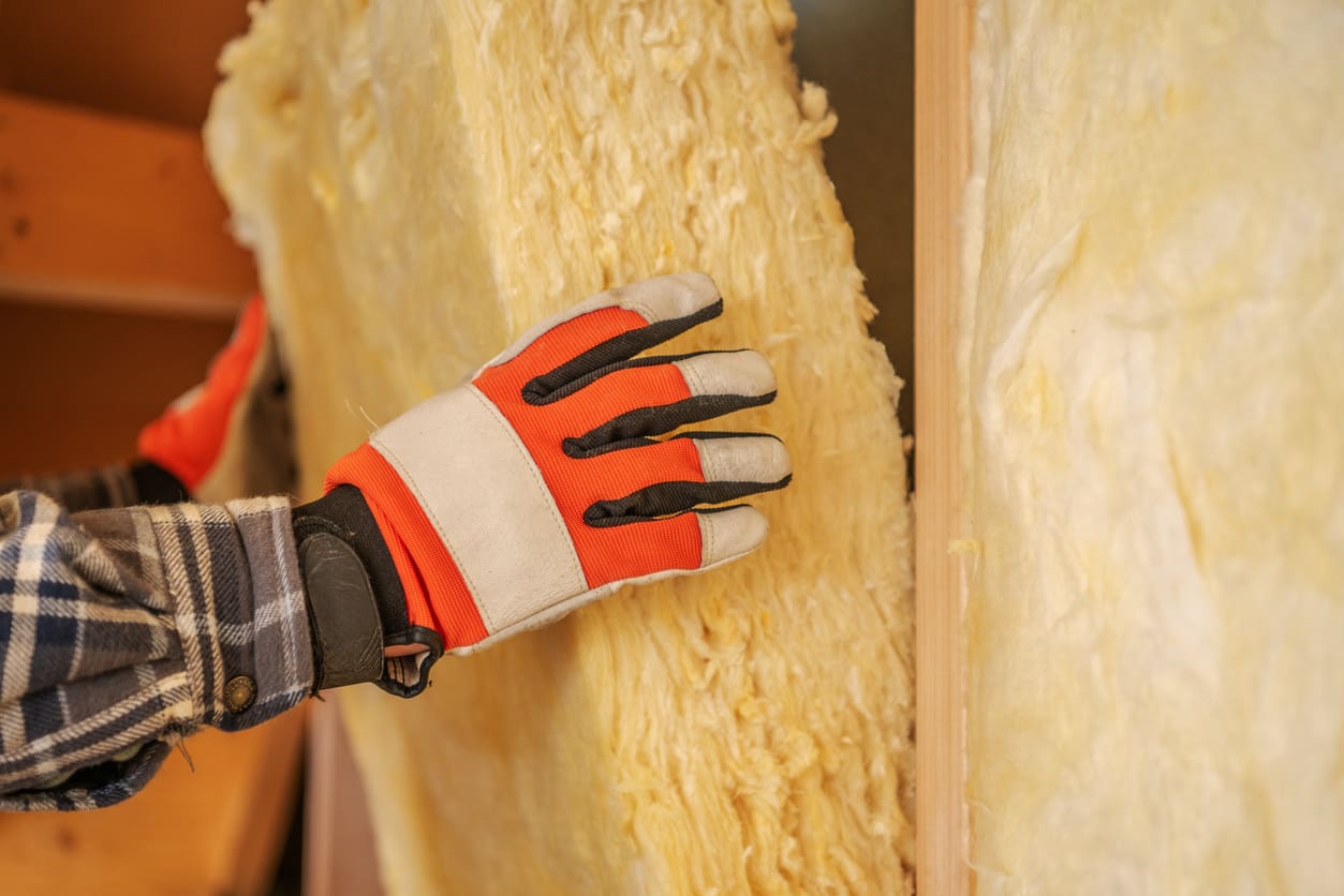 Un travailleur installe un isolant en laine minérale dans sa maison pendant la rénovation 