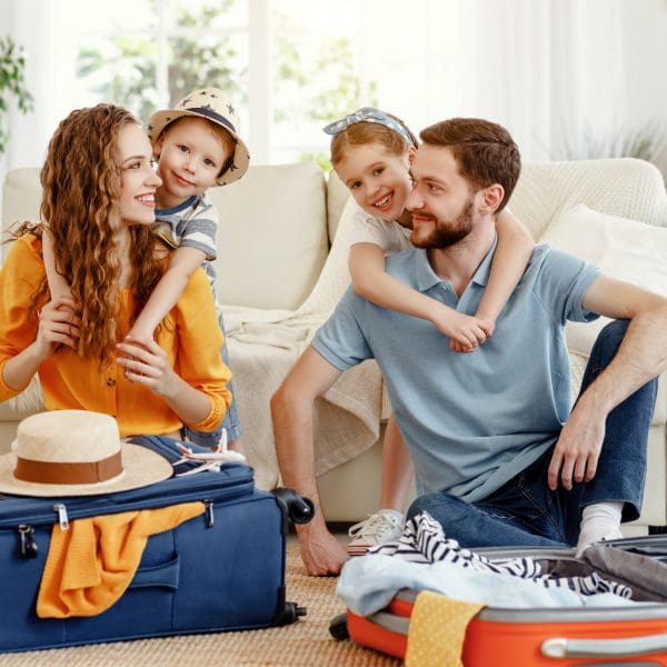 Famille gaie avec des valises sur le plancher regardant l’appareil-photo