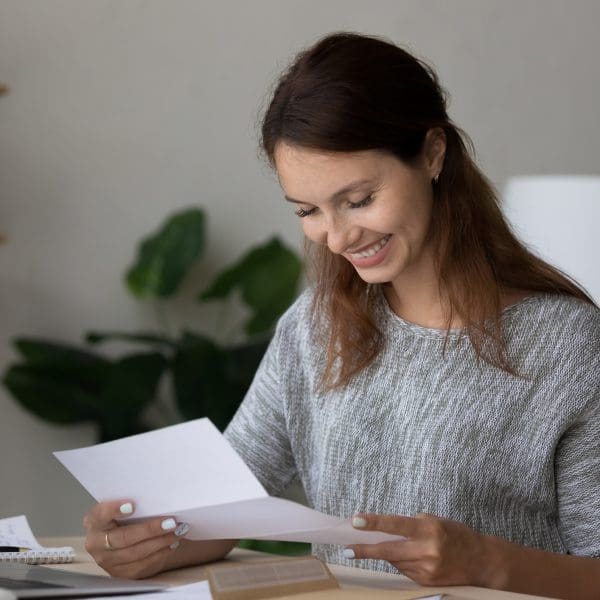 Femme heureuse en train de sourire en lisant un document