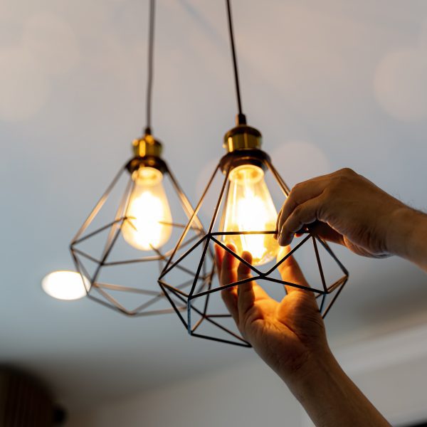 Ampoules à filament décoratives antiques de style edison suspendues. Un électricien installe des projecteurs au plafond