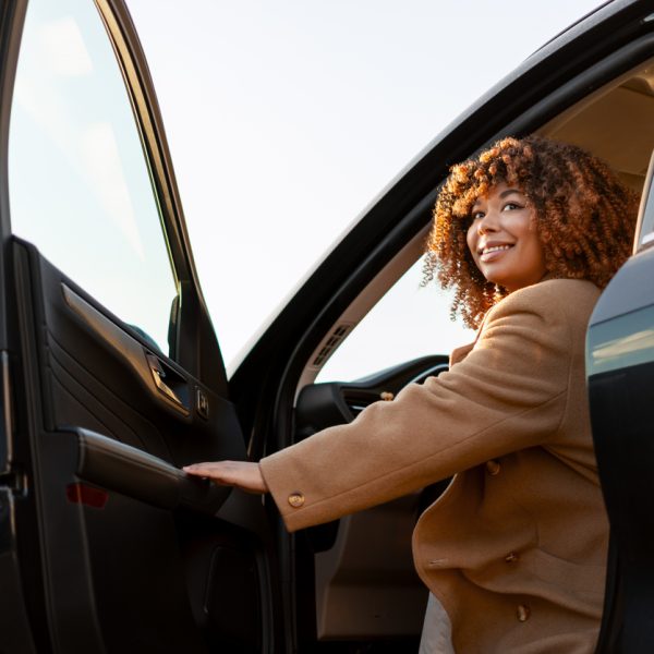 Femme souriante sortant de la voiture, regardant en arrière,