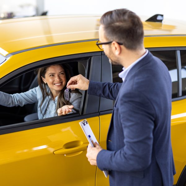 Jeune femme conductrice prenant les clés alors qu’elle est assise dans une voiture de location